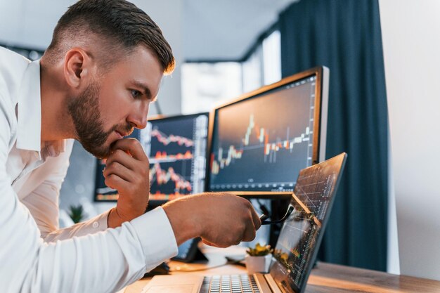 Photo analyzing information young businessman in formal clothes is in office with multiple screens