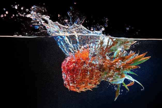 Ananas duiken in het water tegen zwarte muur close-up