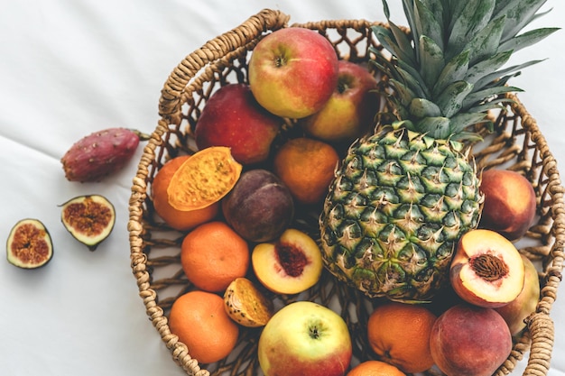 Ananas en ander exotisch fruit in een mand op een witte bovenaanzicht als achtergrond