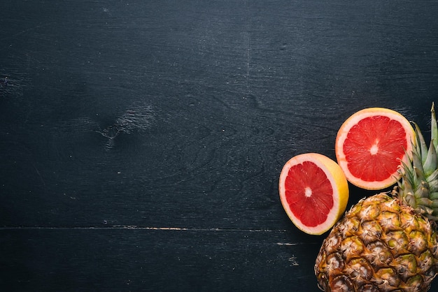 Ananas en citrusvruchten op een houten ondergrond tropische vruchten en noten bovenaanzicht vrije ruimte voor tekst