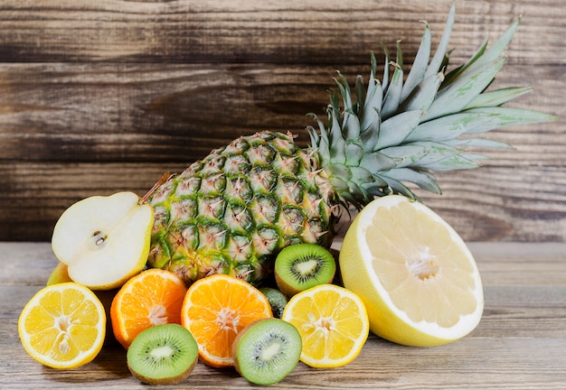 Ananas en gesneden citroen, kiwi, pamela en peer opgestapeld op een achtergrond van hout