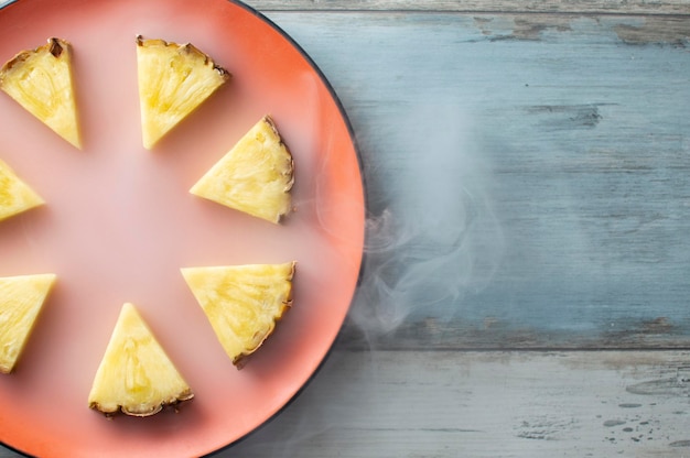 Ananas gesneden piramide ligt op een ronde oranje plaat