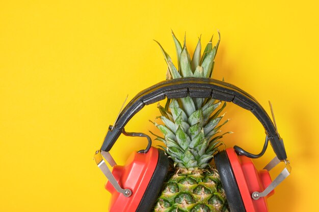 Ananas in rode retro koptelefoon op gele achtergrond