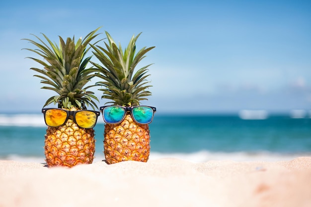 Ananas in stijlvolle zonnebril op het zand tegen zee