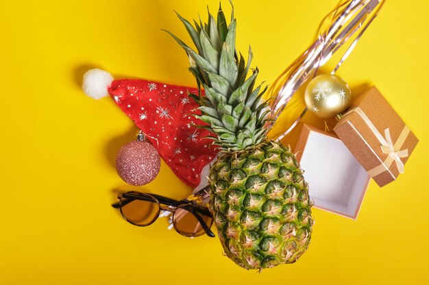 Ananas, kerstmuts en zonnebril, kerstdecor op gele achtergrond