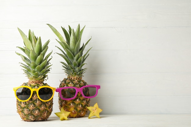 Foto ananas met zonnebril op wit hout, ruimte voor tekst