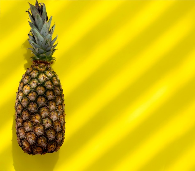 Ananas op gele achtergrond met gestreepte schaduw
