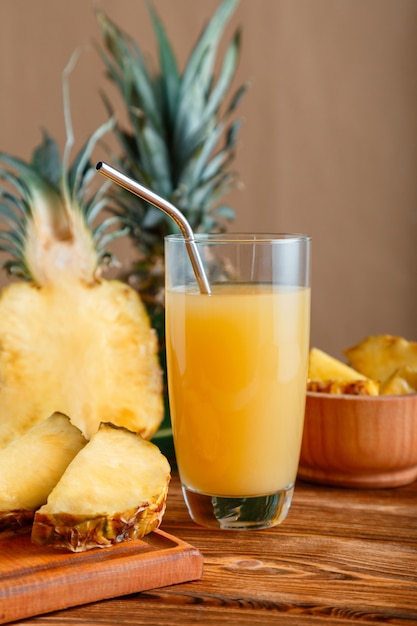 Ananassap in glas. glas verse natuurlijke ananassapcocktail met metalen herbruikbare buis op bruin houten tafel met ingrediënten. rauwe ananas gesneden fruit. hoge kwaliteit stockfoto