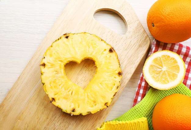 Ananasschijfje met gesneden in de vorm van een hart en verschillende soorten fruit op tafel close-up