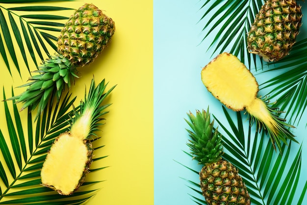 Ananassen, palmbladen op pastelkleur kleurrijke gele en turkooise achtergrond met exemplaarruimte.