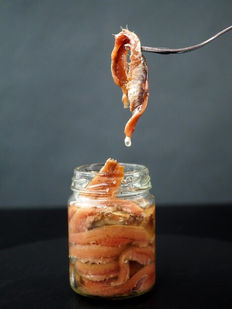 Anchovies in a glass jar on a black background