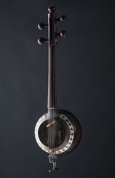 Antico strumento musicale a corde asiatico su sfondo nero con retroilluminazione