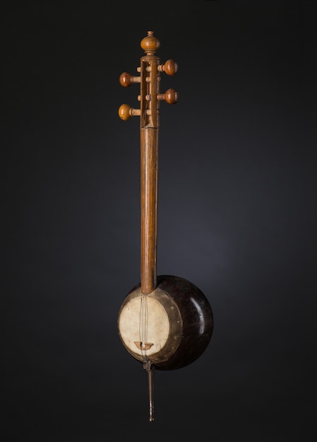 Ancient Asian stringed musical instrument on black background with backlight