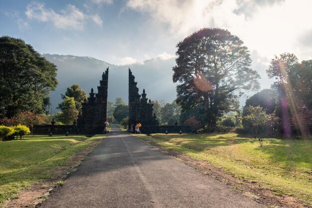 Ancient bali style gate with pathway and shining on tree