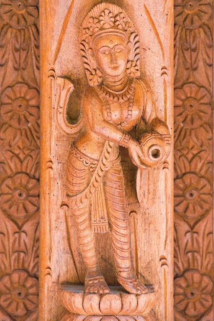 Ancient basrelief woman with a pitcher with floral patterns carved out of wood