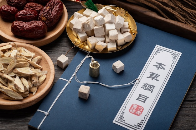 Ancient Chinese medicine books and herbs on the table.