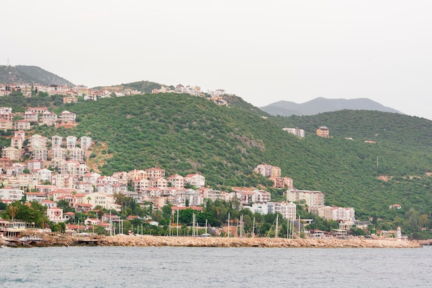 Ancient city with redtiled roofs and white facade of the house in the mountains near the sea view from above