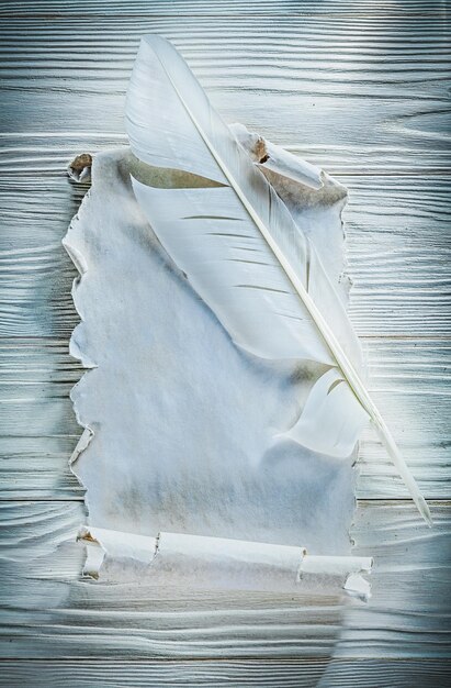 Ancient crumpled paper scroll quill on wooden board.