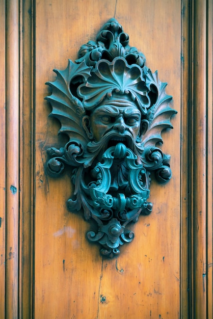 Ancient door knocker on a wooden door in Florence