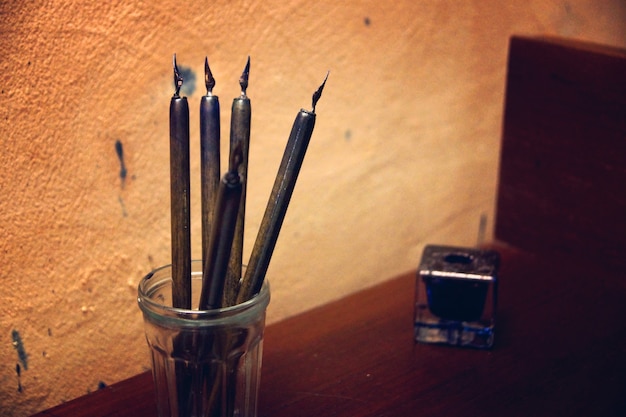 Ancient feather pens on the table next to the inkwell, traces of blots on the wall