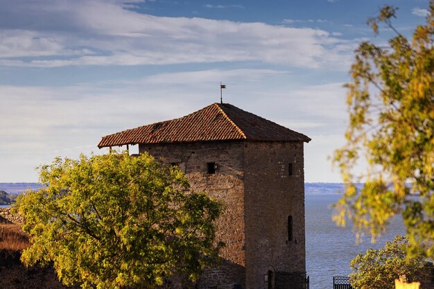 Ancient fortress tower against the background of green trees and blue sky