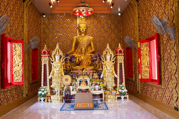 Ancient golden buddha statue in antique ubosot for thai people travelers travel visit and respect praying blessing to holy mystery worship at Wat Maniwong or Mani Wong temple in Nakhon Nayok Thailand