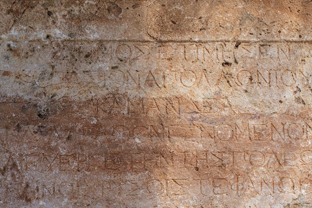 Ancient greek antique text and inscriptions on the stone wall\
of the temple ancient greek culture alphabet and writing background\
history concept