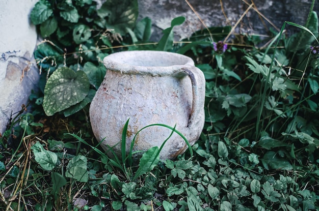 Ancient jug in the grass Old vessel on a blurred background Archeology