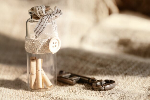 Chiave antica e messaggio di scorrimento in bottiglia con lo sfondo bianco della tela da imballaggio. sfondo di concetto per il giorno di san valentino.