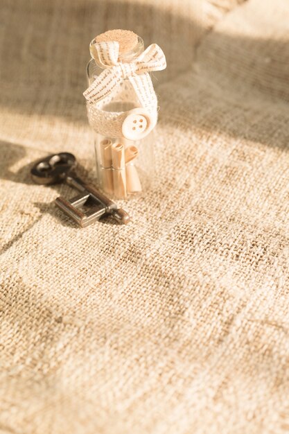 Ancient key and scroll message in the bottle with the white burlap background.Concept background for Valentine's day.