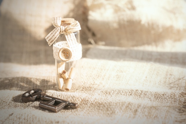 Ancient key and scroll message in the bottle with the white burlap background.Concept background for Valentine's day.