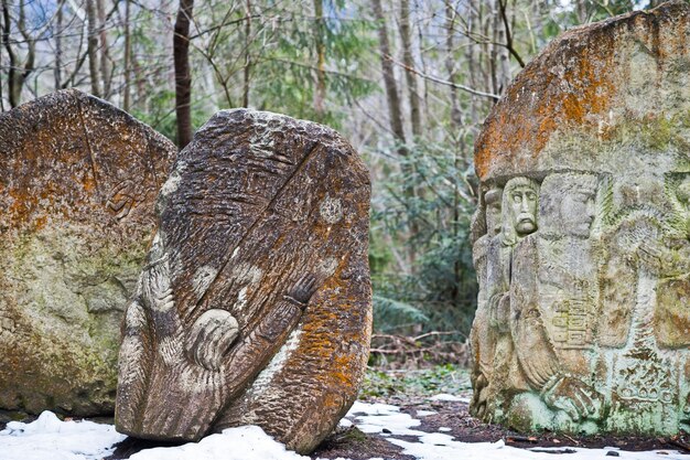 Ancient large stones with engraving at green forest with little snow cover in Carpathians mountains