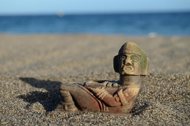 Ancient Maya Statue on the Sand Beach near the Ocean