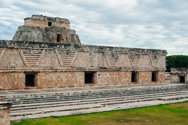 Ancient mayan wall with arches with green garden around in Uxmal Mexico