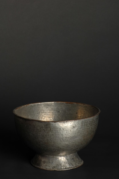 Ancient metal bowl on dark background. antique bronze tableware