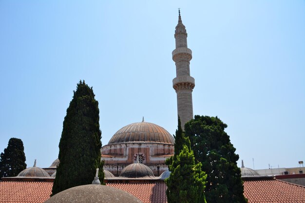 Photo ancient mosque with green trees and blue sky on background, rhodes greece