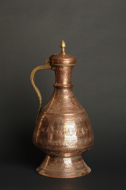 Ancient oriental metal jug on dark background. antique bronze tableware