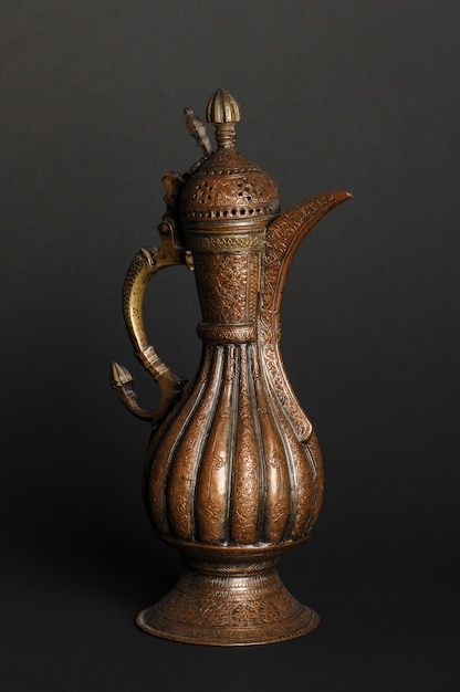 Ancient oriental metal teapot on dark background. antique bronze tableware