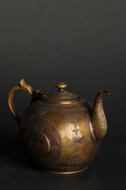 Ancient oriental metal teapot on dark background. antique bronze tableware