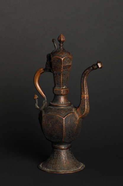 ancient oriental metal teapot on dark background. antique bronze tableware