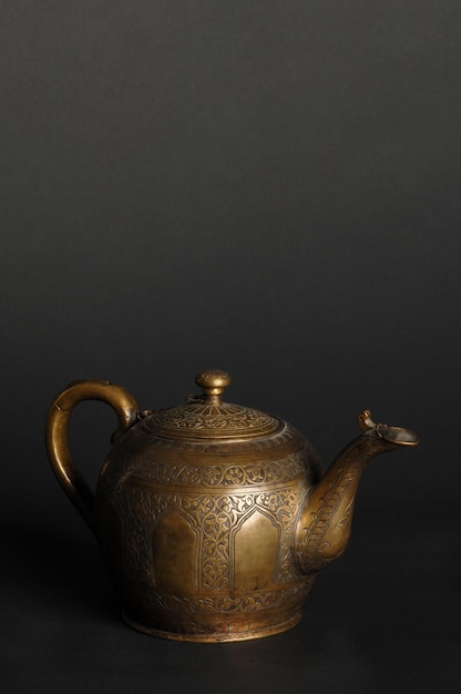 Ancient oriental metal teapot on dark background antique bronze tableware