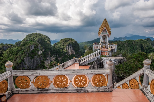 Antica pagoda con altare in alta montagna vicino al tempio della grotta della tigre nella provincia di krabi, thailandia. rocce ricoperte di alberi verdi e cielo coperto con pioggia all'orizzonte.