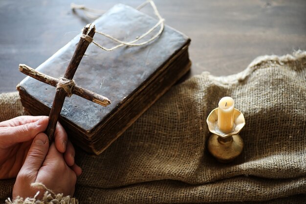 Фото Древняя религиозная книга и деревянный крест на фоне деревянной и мешковины