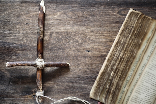 Ancient religious book and wooden cross on the background of a wooden and burlap