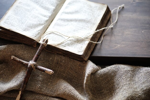 Ancient religious book and wooden cross on the background of a wooden and burlap