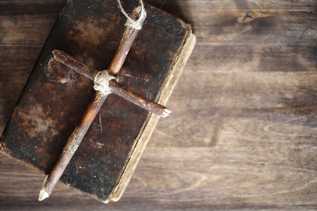 Antico libro religioso e croce di legno sullo sfondo di un legno e tela