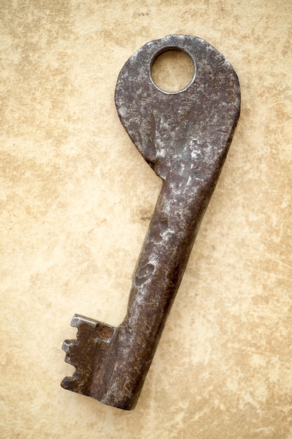 Ancient rusty key on vintage cardboard background