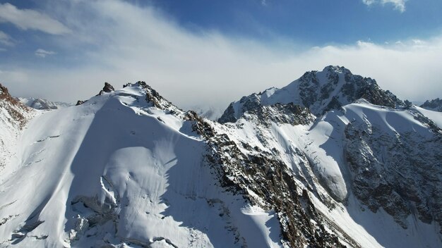 An ancient snow glacier among high mountains. In places there are steep cliffs and large rocks.