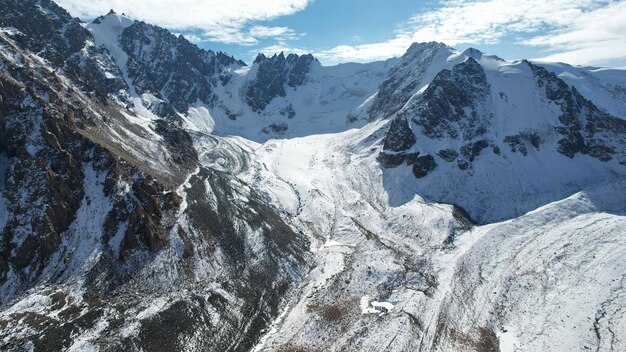 An ancient snow glacier among high mountains. In places there are steep cliffs and large rocks.