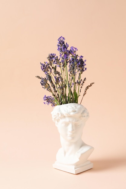 Testa di statua antica con bellissimi fiori di lavanda